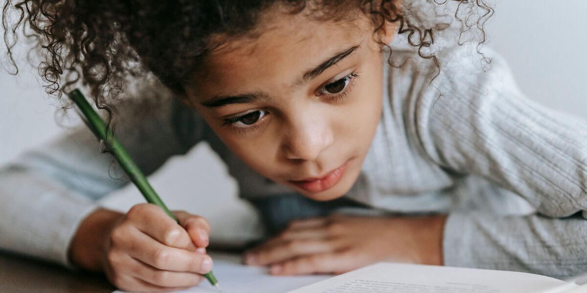 Niño practicando la escritura con lápiz sobre su cuaderno